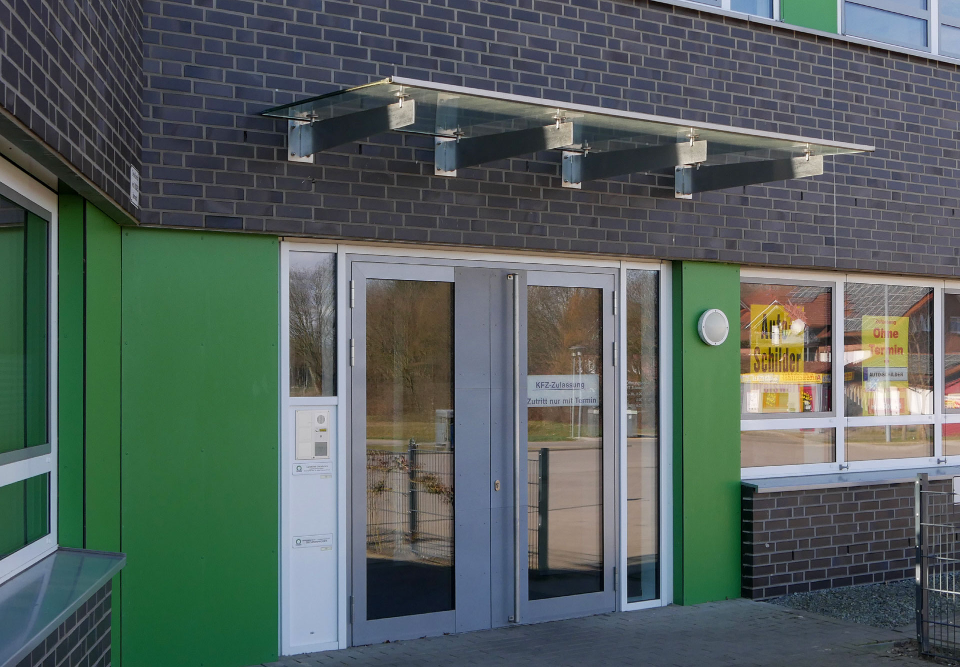 Eingangsbereich des Logistikzentrums Bersenbrück mit Aluminiumtür und Glasvordach von Klövekorn Metall