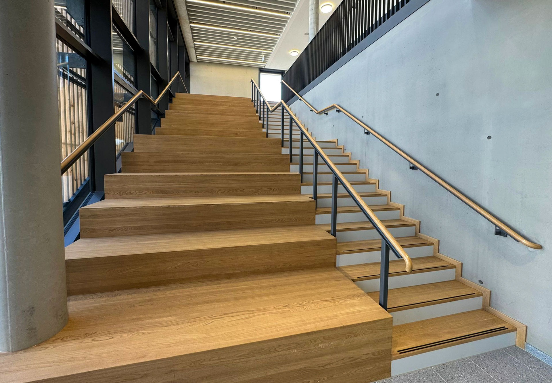 Treppe mit Holzhandlauf und Metallgeländer im Schulgebäude