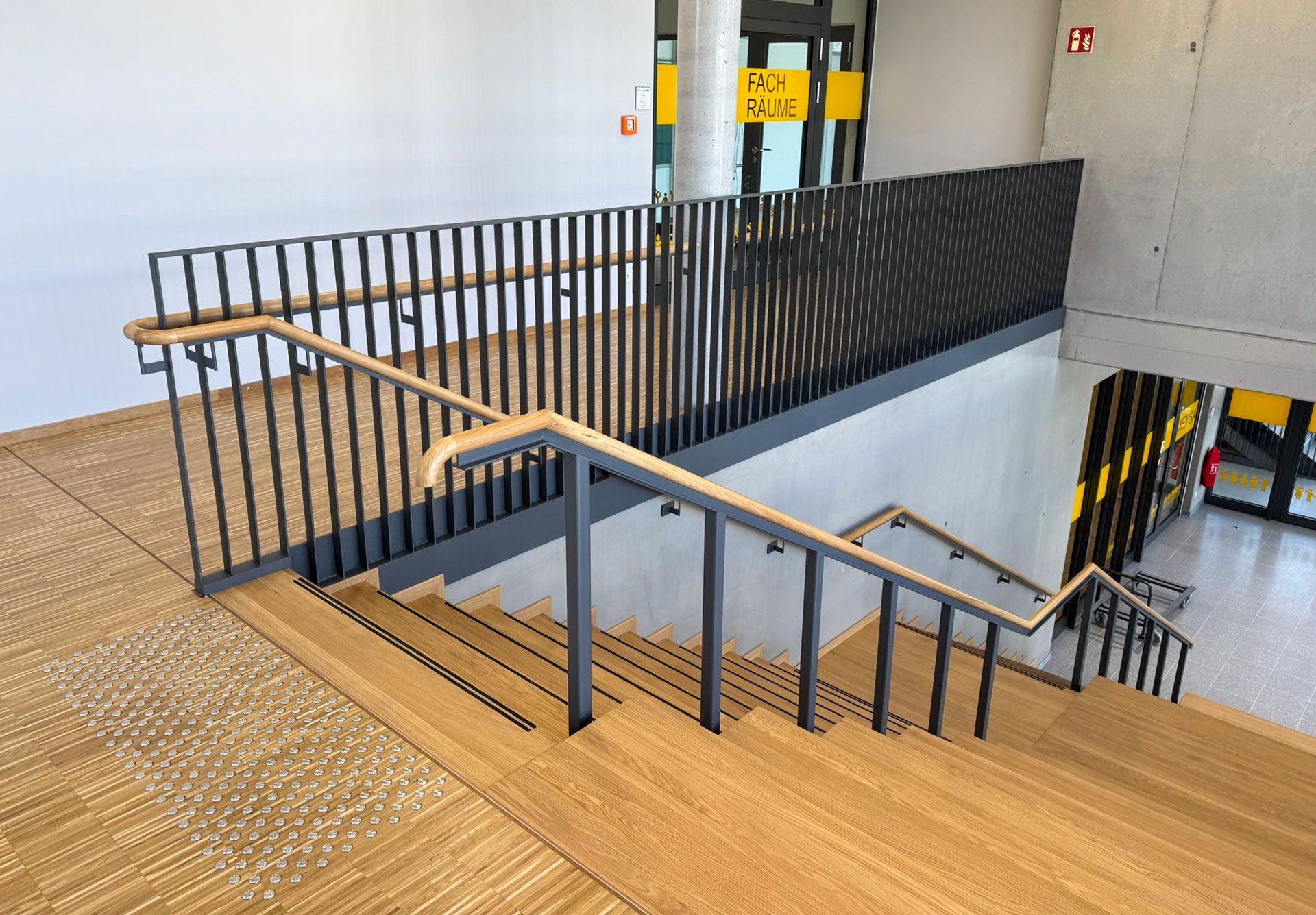 Moderne Treppe mit Holzstufen und schwarzem Metallgeländer