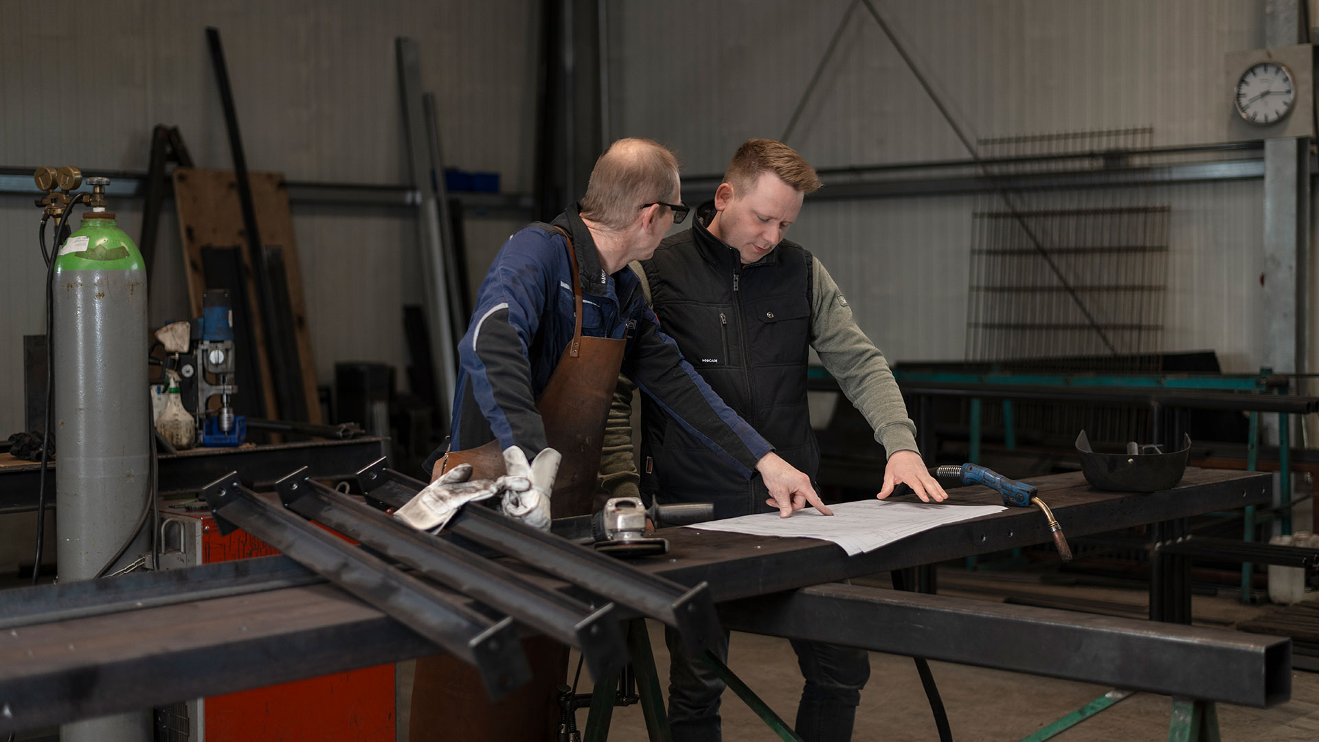 Zwei Mitarbeiter von Klövekorn Metall bei der gemeinsamen Besprechung von Bauplänen in der Werkstatt